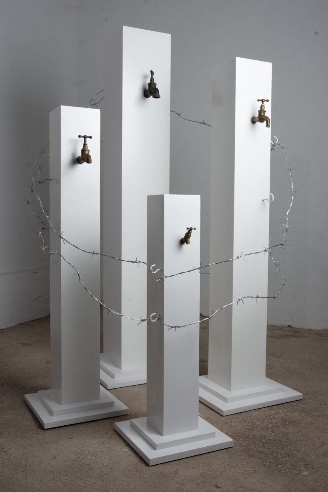 Die vier von Stacheldraht umzäunten, weißen Türme der Installation von Christina Lag-Schröckenstein erzählen von den Absurditäten einer Menschheit, die Globalisierung als egozentrischen Prozess ohne Gerechtigkeit und Balance missverstanden hat. Sie erzählen von Konzernen, die den Menschen erst das Wasser und andere Rohstoffe entwenden, um sie ihnen dann teuer zu verkaufen